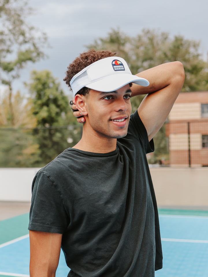 Man wearing white CO Love Colorado flag trucker visor on tennis court — Bear & Sarge