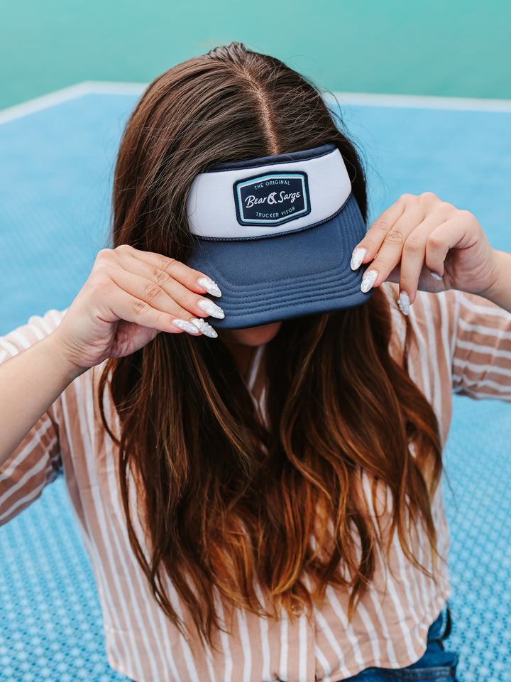 Woman adjusting navy Retro B+S trucker visor on court — Bear & Sarge