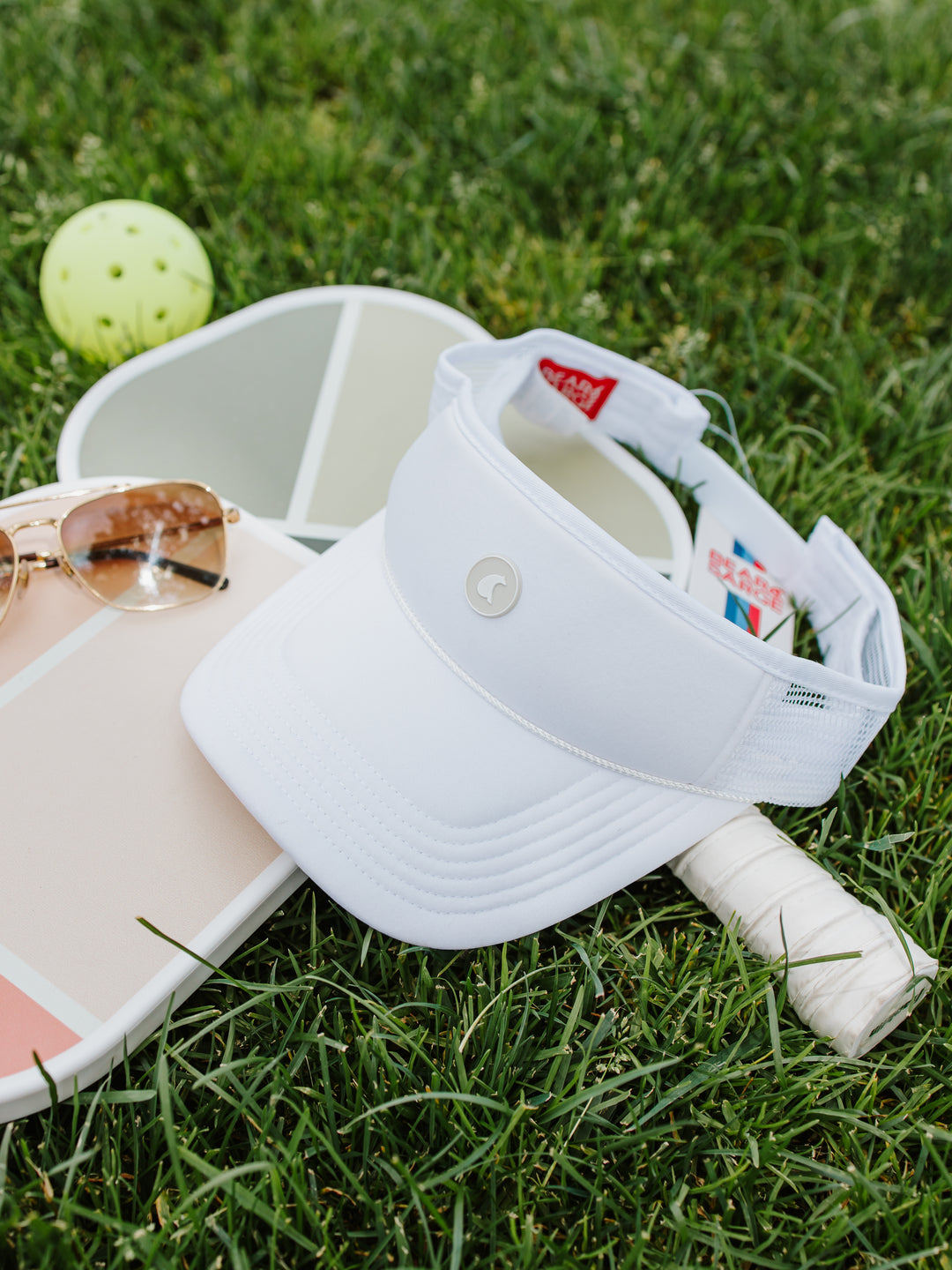 White B+S Bear trucker visor with pickleball paddle and ball on grass — Bear & Sarge